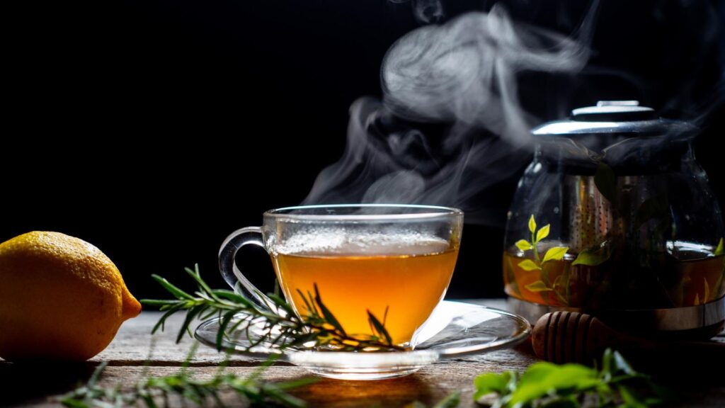 Freshly brewed rosemary tea in a clear glass cup with lemon and herbs, showcasing herbal tea benefits for digestion, immunity, and relaxation.