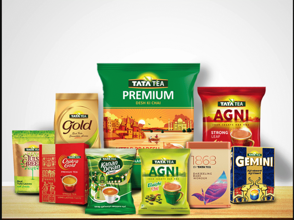 Tata Tea product range including Tata Tea Premium, Tata Tea Gold, Tata Tea Agni, Kanan Devan, Chakra Gold, Tulsi Green Tea, 1868 Darjeeling Tea, and Gemini Tea displayed together on a wooden surface.
