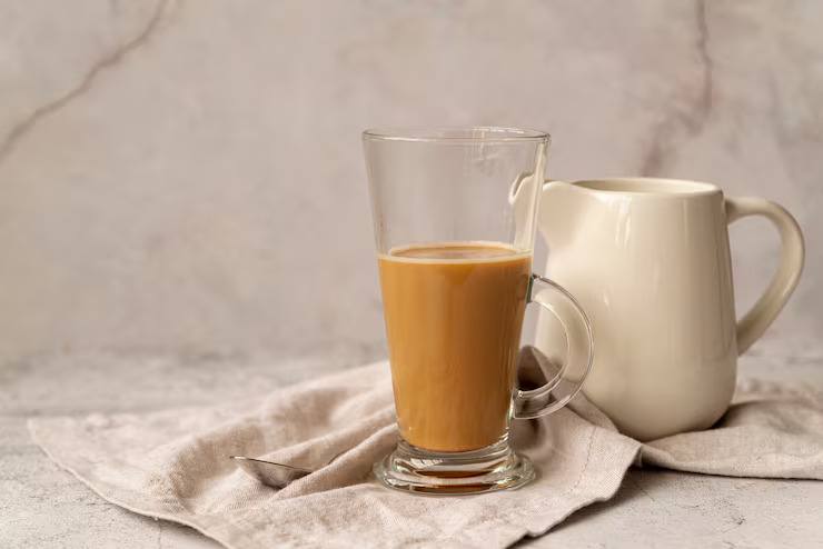 Glass cup of freshly brewed milk tea placed on a neutral fabric setting, showcasing creamy chai tea with a smooth and comforting appearance.