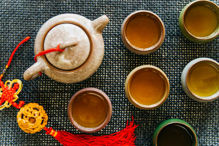 Traditional Chinese tea set with Da Hong Pao brewed teas served in multiple ceramic cups and a teapot on a woven mat.