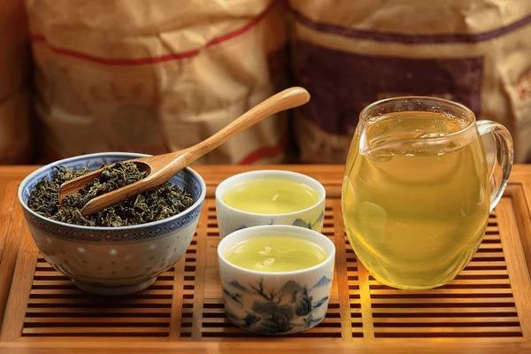 Loose Tieguanyin Tea leaf with teacups and glass teapot arranged on a wooden tea tray for tea tasting.